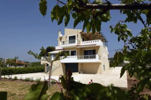 a white house with a balcony on top of it at Panelma Villa Tranquil Coastal Retreat in Zacharo in Tholón