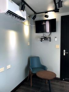 a room with a blue chair and a table and a tv at Saipan Skyline Designers Hotel in Saipan