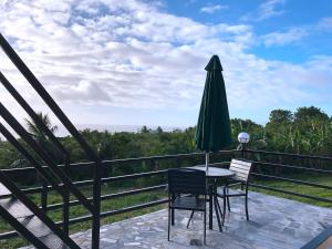 a table with chairs and a green umbrella on a balcony at Saipan Skyline Designers Hotel in Saipan