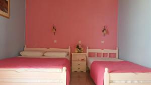 two beds in a room with pink walls at Bella Vista in Nydri