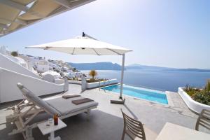 a patio with an umbrella and a swimming pool at Santorini Secret Suites & Spa, Small Luxury Hotels of the World in Oia