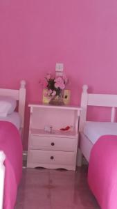 sypialnia z różowymi ścianami i białą komodą z kwiatami w obiekcie Bella Vista w mieście Nydri