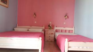 two beds in a room with pink walls at Bella Vista in Nydri