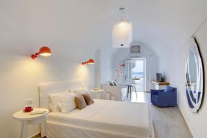 a white bedroom with a bed and a living room at Santorini Secret Suites & Spa, Small Luxury Hotels of the World in Oia