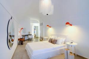 a white bedroom with a white bed and a table at Santorini Secret Suites & Spa, Small Luxury Hotels of the World in Oia