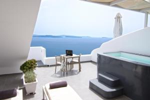 a balcony with a plunge pool and a table and chairs at Santorini Secret Suites & Spa, Small Luxury Hotels of the World in Oia