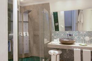 a bathroom with a sink and a shower at Santorini Secret Suites & Spa, Small Luxury Hotels of the World in Oia