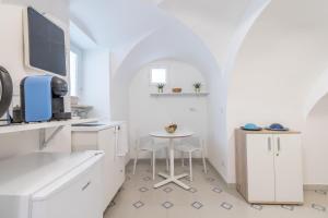 kuchnia z białymi szafkami i małym stołem w obiekcie To Be Capri w mieście Capri