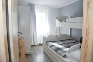 a small white bedroom with a bunk bed and a window at 4 STRONY ŚWIATA Dom Gościnny in Dźwirzyno