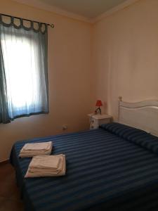 Un dormitorio con una cama con una manta de rayas azules y una ventana en Residenza Rosmarini, en Palau