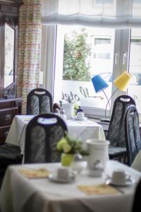 a dining room with two tables and chairs and a window at Hotel Alscher in Leverkusen