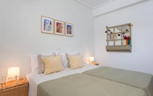 a white bedroom with a bed and two lamps at Comfortable house with amazing view in Anavyssos