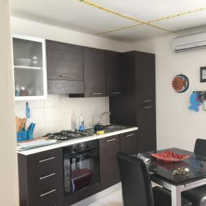 a kitchen with dark brown cabinets and a table with a dining room at Appartamenti Tre Vele in Trapani