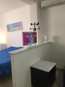 トラーパニにあるAppartamenti Tre Veleの壁にテレビとベッドが備わる客室です。