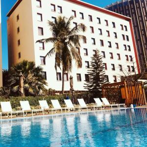 a hotel with a swimming pool in front of a building at Ibis Dakar in Dakar
