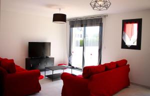 ein Wohnzimmer mit roten Sofas und einem TV in der Unterkunft Le Brin d'Sologne in Contres