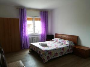 Schlafzimmer mit einem Bett und einem Fenster mit lila Vorhängen in der Unterkunft Venice Amazing House in Marghera
