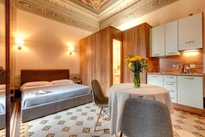 een slaapkamer met een bed en een tafel met een vaas met bloemen bij Sleep Tight Florence Apartment in Florence