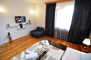 ein Wohnzimmer mit einem Bett, einem Sofa und einem TV in der Unterkunft Mia's Apartment in Tbilisi City