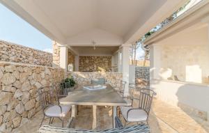 a patio with a table and chairs and a stone wall at Villa Toma I in Novalja