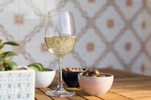a glass of white wine next to a bowl of nuts at Ondina Guesthouse in Casais de São Lourenço
