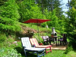 a group of chairs and a table with an umbrella at Holiday Home Forest Peace, Lavrovec in Hlevni Vrh