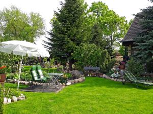 a garden with a table and chairs and an umbrella at Pension Zum weißen Hirsch in Reitwein