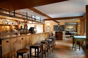 a bar in a restaurant with wooden walls and stools at The Museum Inn in Farnham