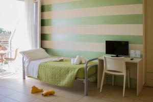 Dormitorio con cama, escritorio y TV en The Lighthouse Rooms, en Lazise