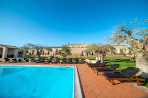 una piscina con sedie e sedie accanto a un edificio di Torre Don Virgilio Country Hotel a Cannizzara