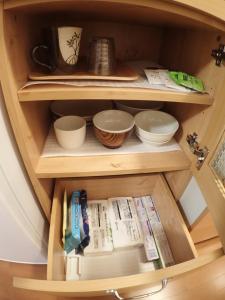 a wooden cabinet with bowls and other dishes in it at Kuganipi Beachside Inn Iriomote in Iriomote