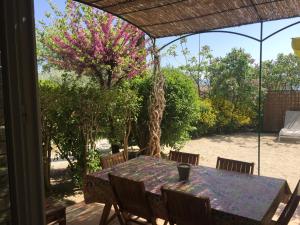 una mesa con sillas y un árbol con flores rosas en Bastidon la Cicada, en Gordes