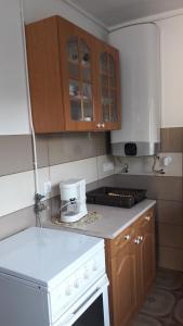 eine Küche mit Holzschränken und einer weißen Arbeitsplatte in der Unterkunft Simon Apartmanház Zamárdi in Zamárdi