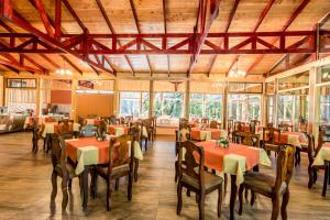 a dining room with tables and chairs and windows at Sueños del Bosque Lodge in San Gerardo de Dota