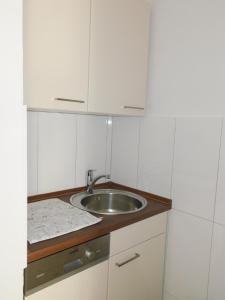 a small kitchen with a sink and white cabinets at Nordsee in Nordstrand