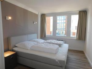 een slaapkamer met een bed met witte lakens en een raam bij Nordsee in Nordstrand