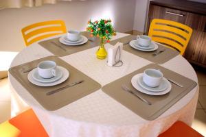 una mesa con platos y tazas y un jarrón con flores en Mais Hotel, en Araguaína