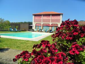a house with red flowers next to a swimming pool at Casa do Varandão in Barcelos