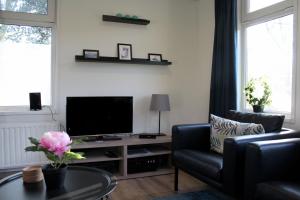 a living room with a tv and a chair and a table at Houseboat Linquenda in Woubrugge