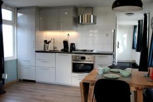 a kitchen with white cabinets and a wooden table at Houseboat Linquenda in Woubrugge