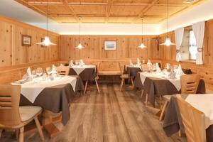 una sala da pranzo con tavoli, sedie e pareti in legno di Das Mitterplarser Hotel a Lagundo