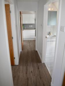 um corredor que leva a uma cozinha com armários brancos em 24 Old Scapa Road em Kirkwall