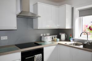 a kitchen with white cabinets and a sink and a microwave at 24 Old Scapa Road in Kirkwall