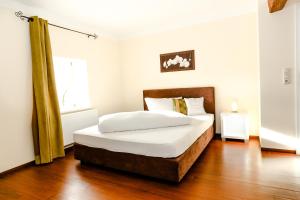 Schlafzimmer mit einem Bett mit weißer Bettwäsche und Holzböden in der Unterkunft Pension Ferber in Monheim
