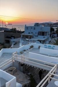 einen Sonnenuntergang über einem weißen Gebäude mit dem Meer in der Unterkunft Pension Alexandra Mykonos port in Mykonos Stadt