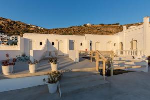 un groupe de bâtiments blancs avec des escaliers et des plantes dans l'établissement Pension Alexandra Mykonos port, à Mykonos