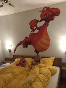 zwei Kinder auf einem Bett mit einem Drachen an der Wand in der Unterkunft Ruster Drachennest in Rust