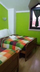 a bedroom with a bed with green walls and a window at Residencial Moeda in Coimbra