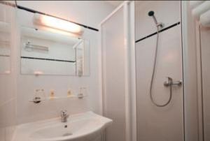 a white bathroom with a sink and a shower at Sky Hotel Goussainville Charles de Gaulle in Goussainville