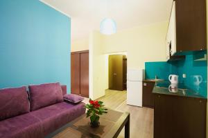 salon z fioletową kanapą i kuchnią w obiekcie Apartment Fedkovycha w Lwowie
